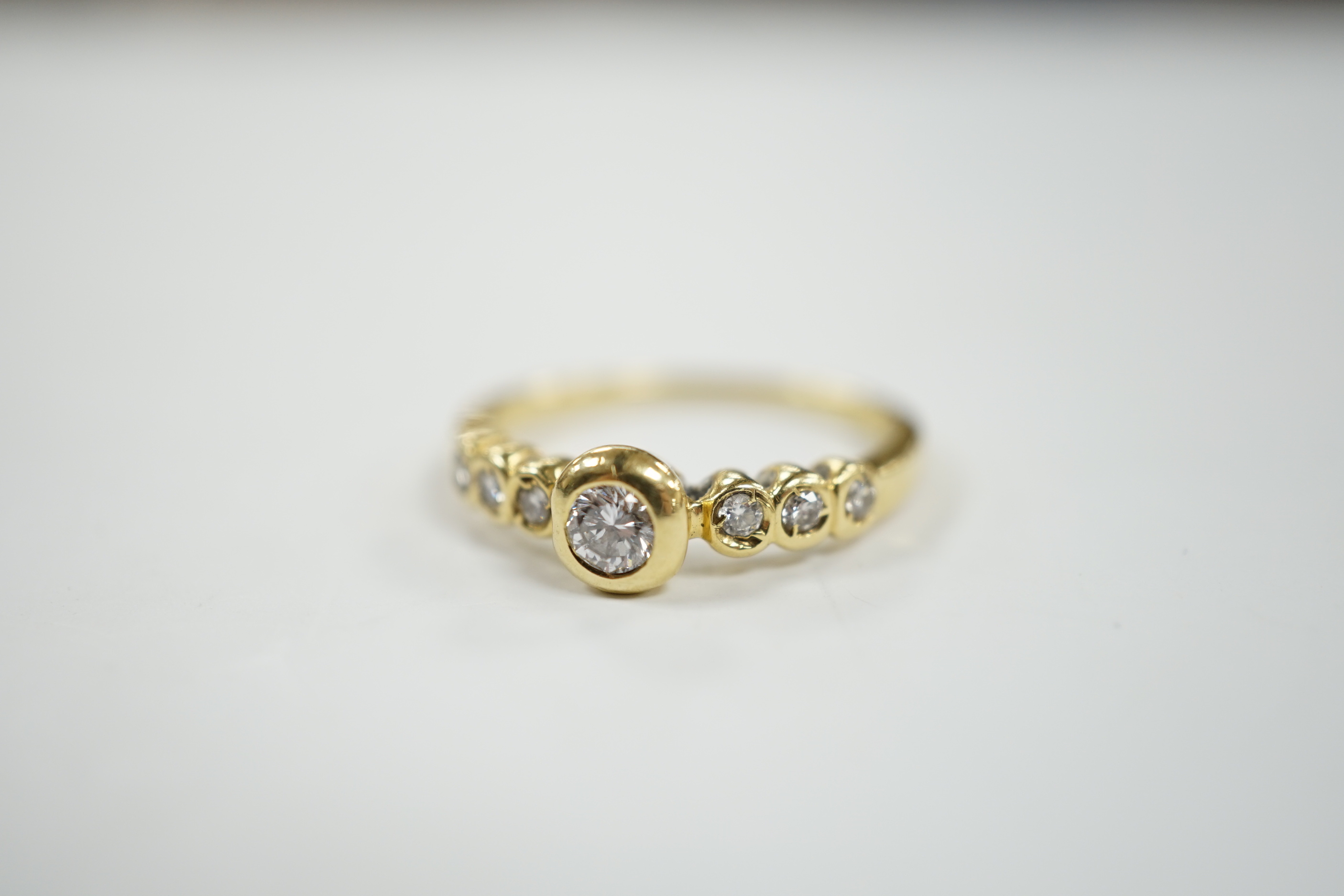 A 750 yellow metal and seven stone diamond set half hoop ring, size O, gross weight 3.6 grams.